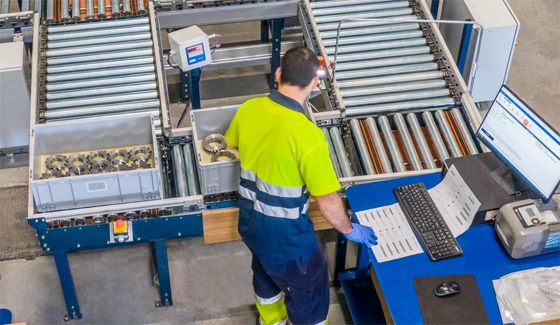Worker processing parts at a workstation next to roller conveyors