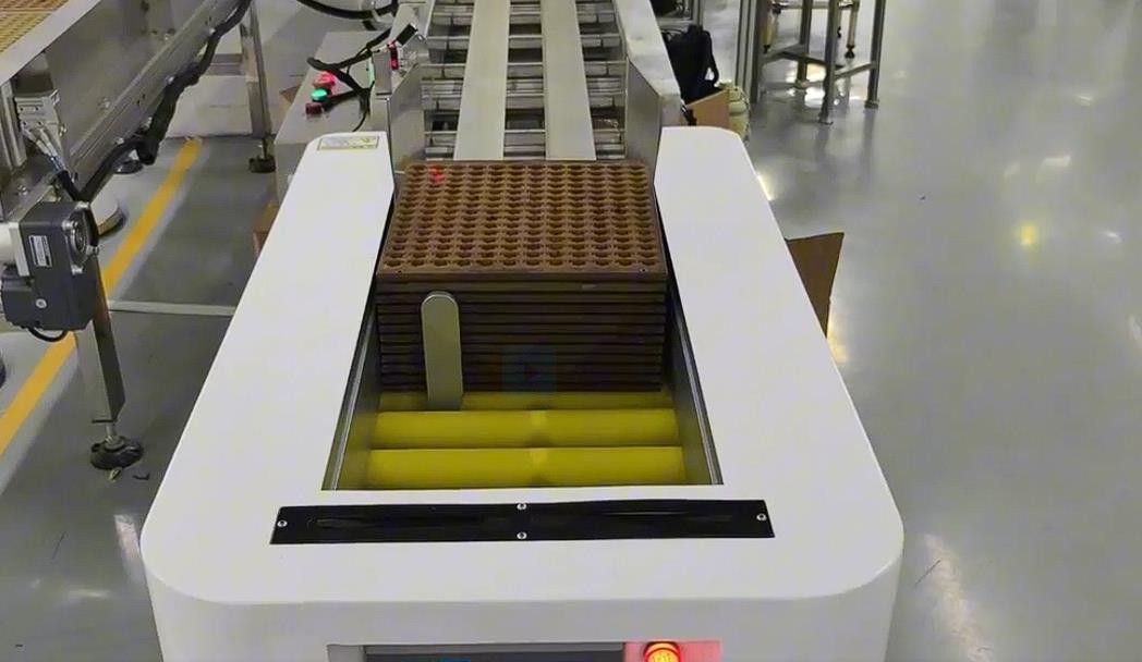 Automated interface conveyor transferring trays in an electronics production logistics system
