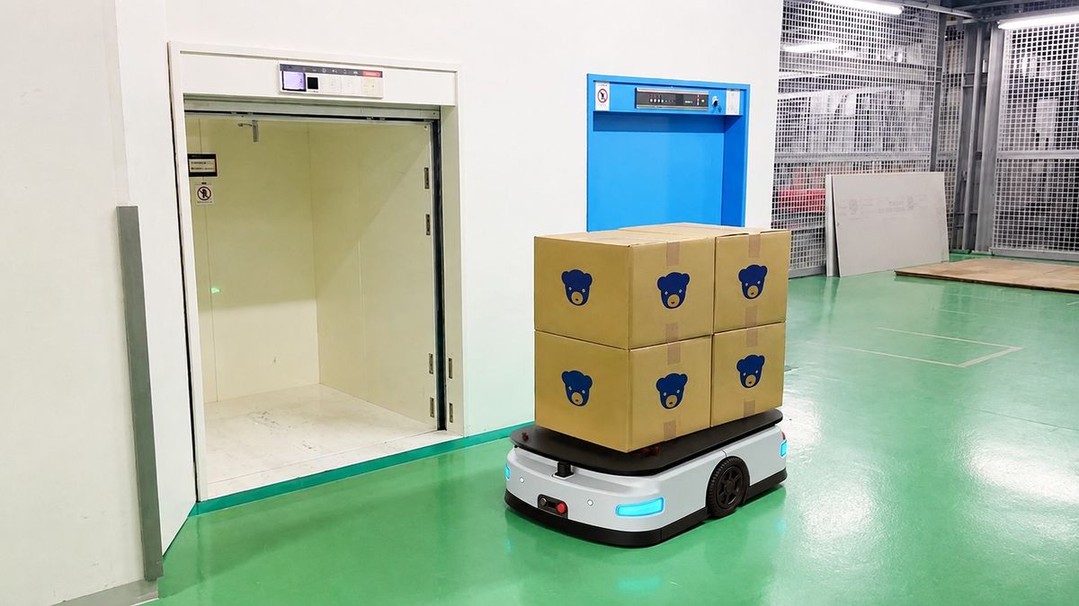 AGV carrying cartons near a freight elevator for multi-floor electronics workshop logistics