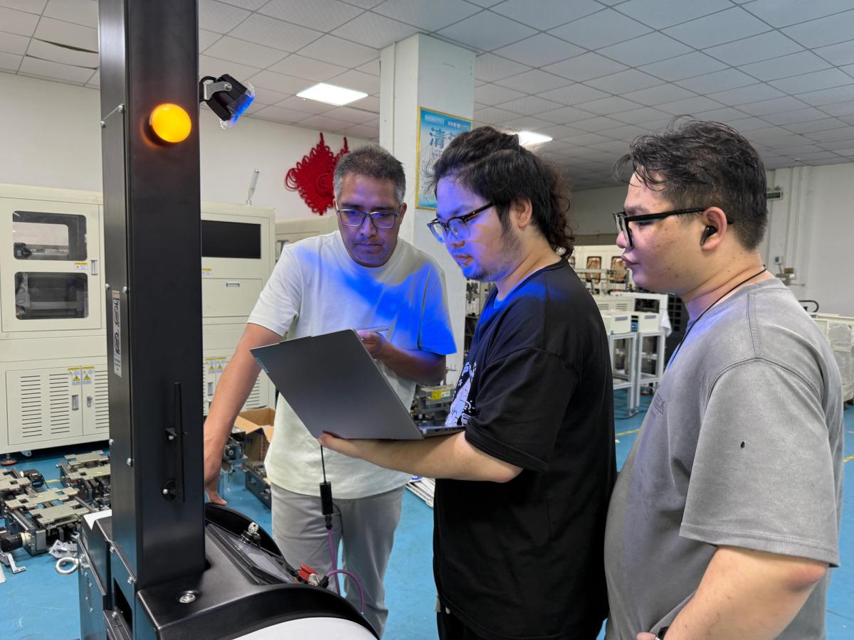 Project team assessing autonomous forklift AGV performance with a laptop