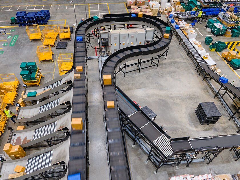Conveyor system moving cartons through a warehouse material handling process