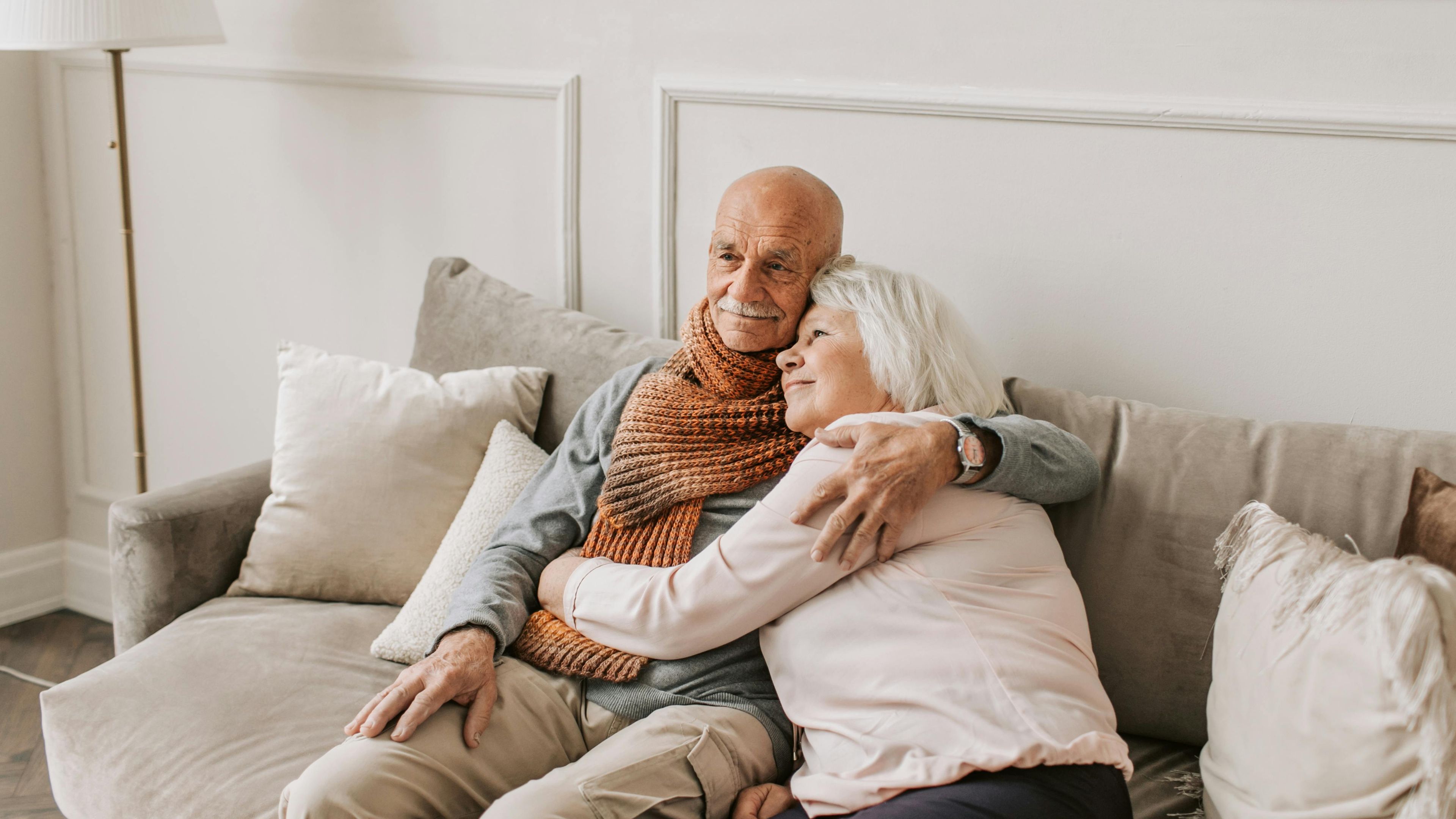 an elderly couple is sitting on a couch hugging each other .