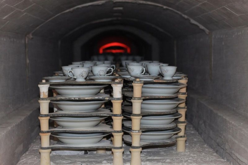 Pratos e xícaras empilhados em placas dentro do forno aceso