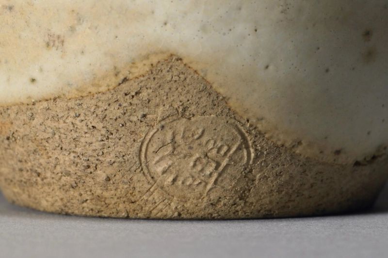 Detalhe do pé de uma garrafa, com a marca carimbada no barro