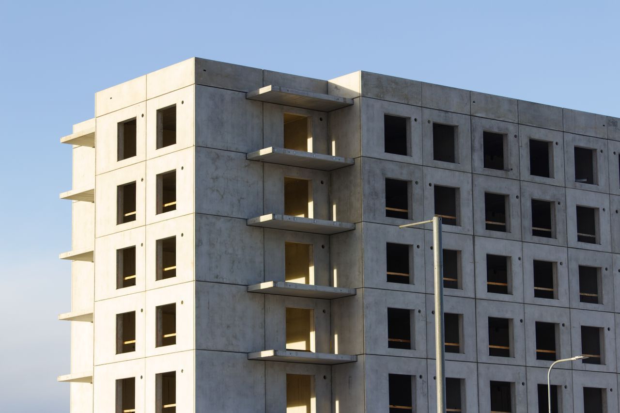 Unfinished multi-storey concrete building under soft daylight — a muted geometric shell suggesting work paused after the structure was up