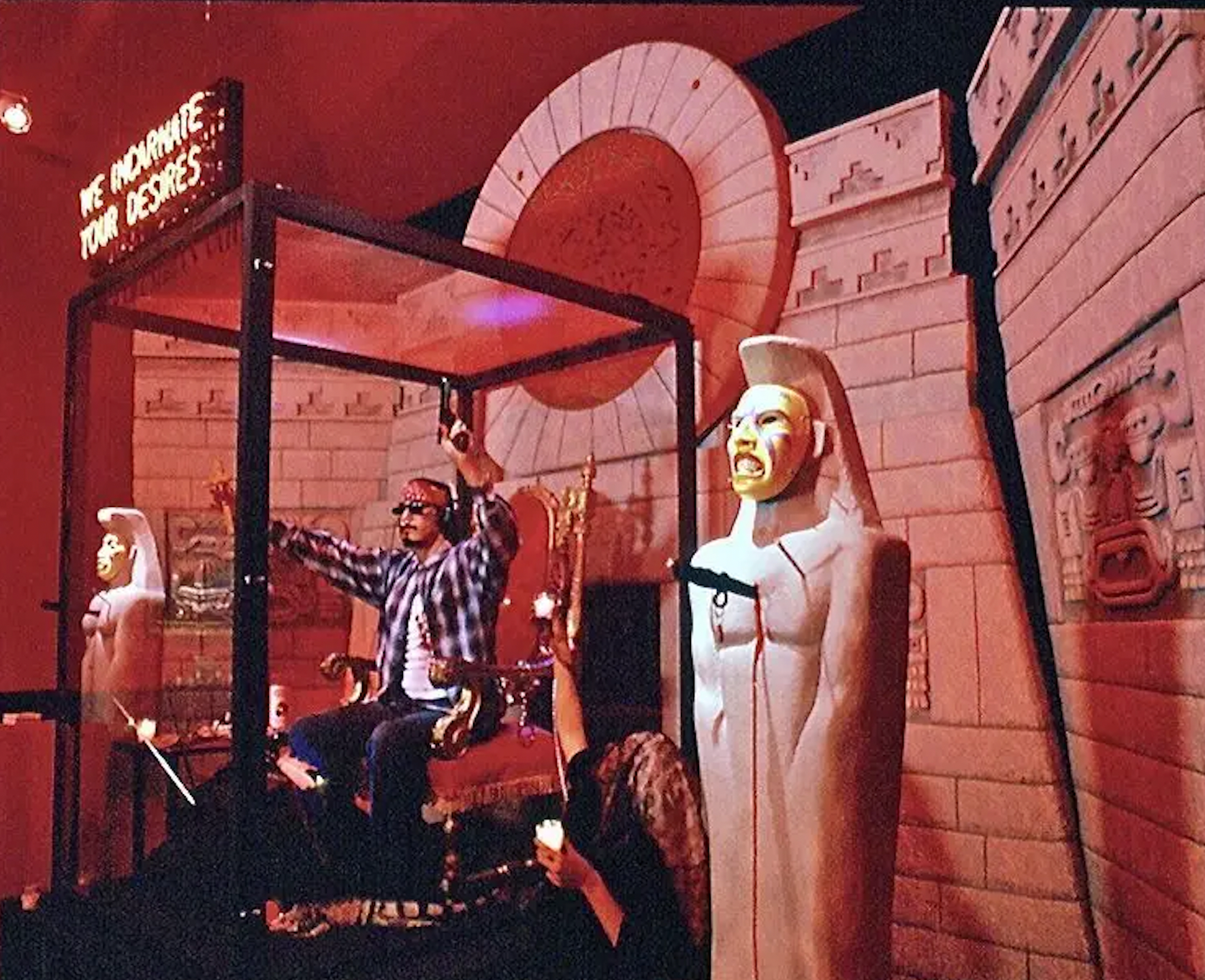 Roberto Sifuentes seated inside a glass cabinet surrounded by ritual artifacts.