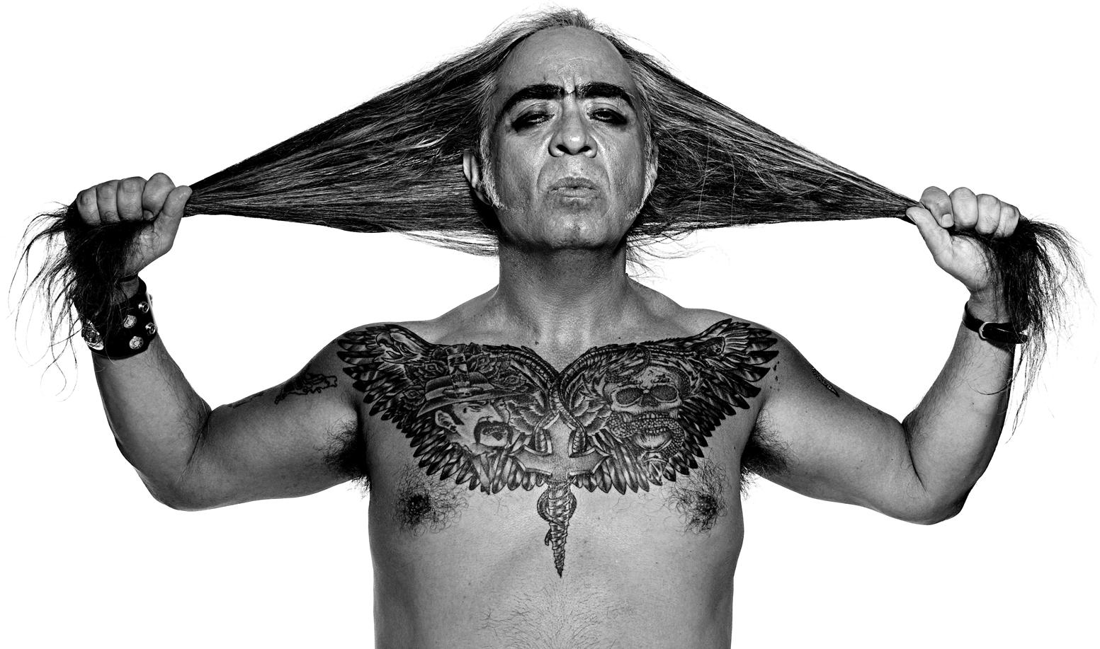 GGP, bare-chested and tattooed, arms upraised, pulls his hair.