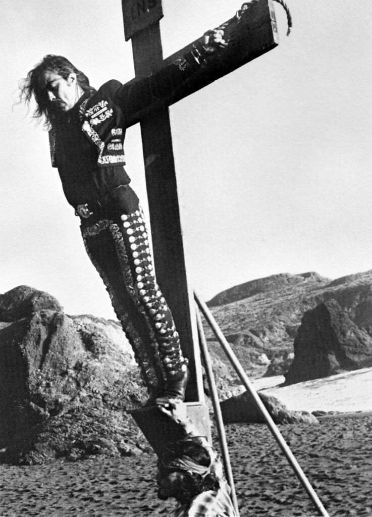 Guillermo Gómez-Peña suspended from a crucifix.