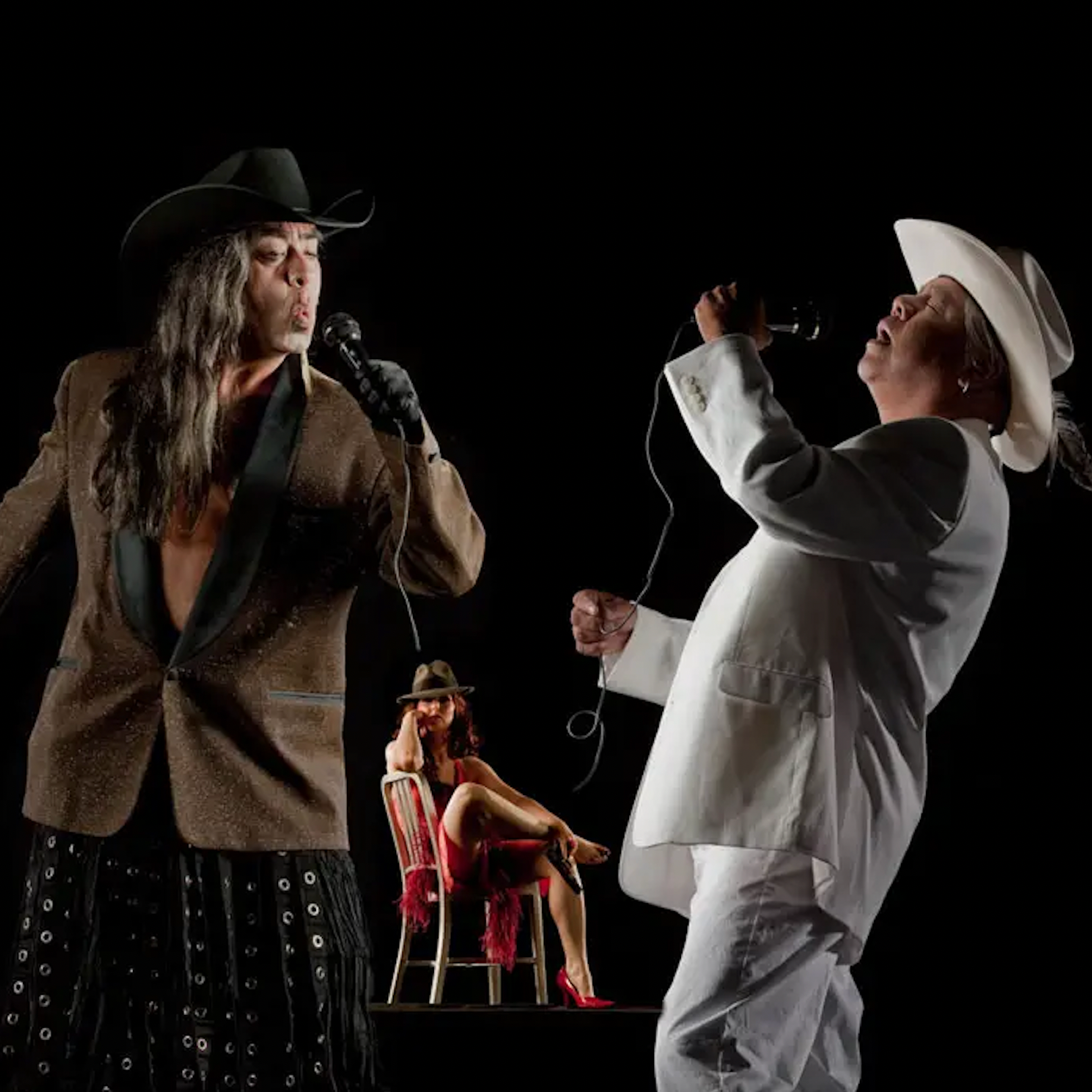 Gómez-Peña and James Luna dressed in suit coats singing into microphones