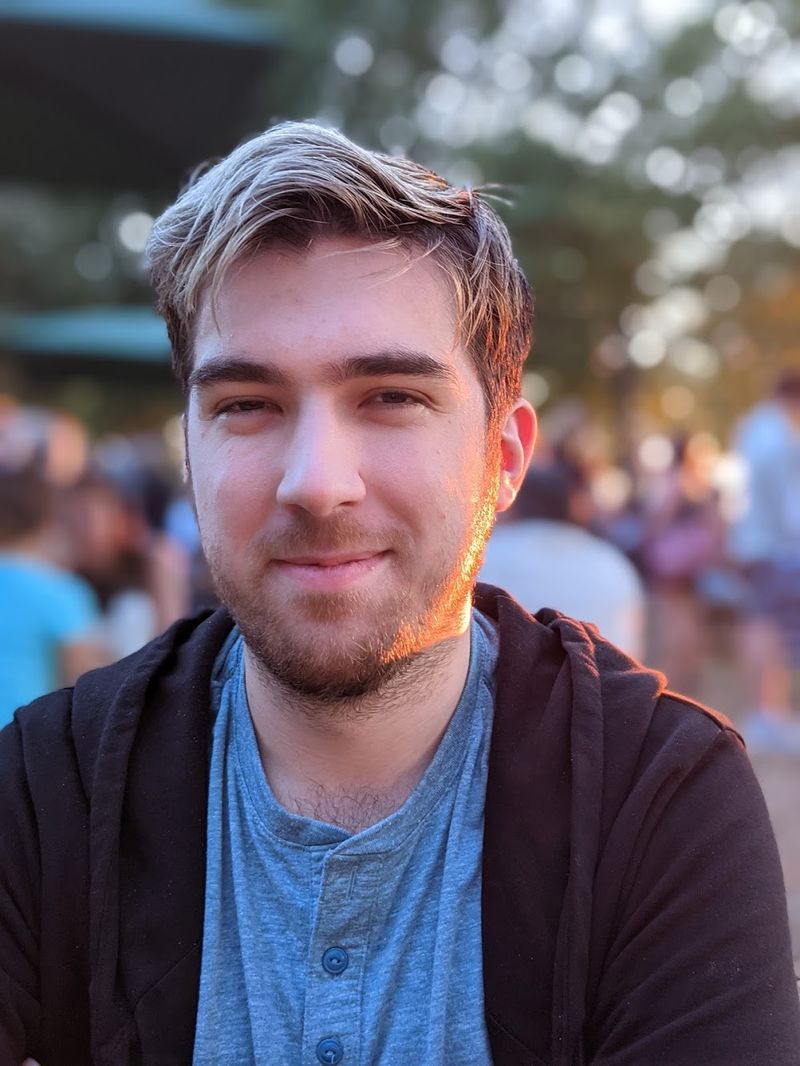 Ray smiles at the camera, with a blue shirt, silver hair, and great 'tude.