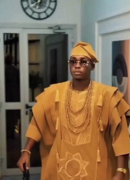 slim gold dress watch peeking beneath an agbada sleeve, a West African elegance code that predates the global quiet luxury trend.