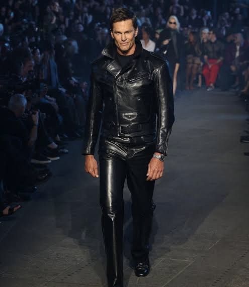 Tom Brady walks the GucciCore runway at Times Square, Gucci Cruise 2027, wearing a leather jacket from the collection.