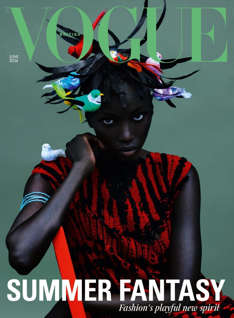 Anok Yai on the cover of VOGUE's UK June 2026 Edition. Image shows Anok Yai in close up, seated wearing a black and red dress, and photographed against a green background with bird details visible in her hair and at her shoulder. Above her head, the vogue strapline in a lighter shade of green. The cover line reads: "Summer Fantasy Fashion's Playful New Spirit."