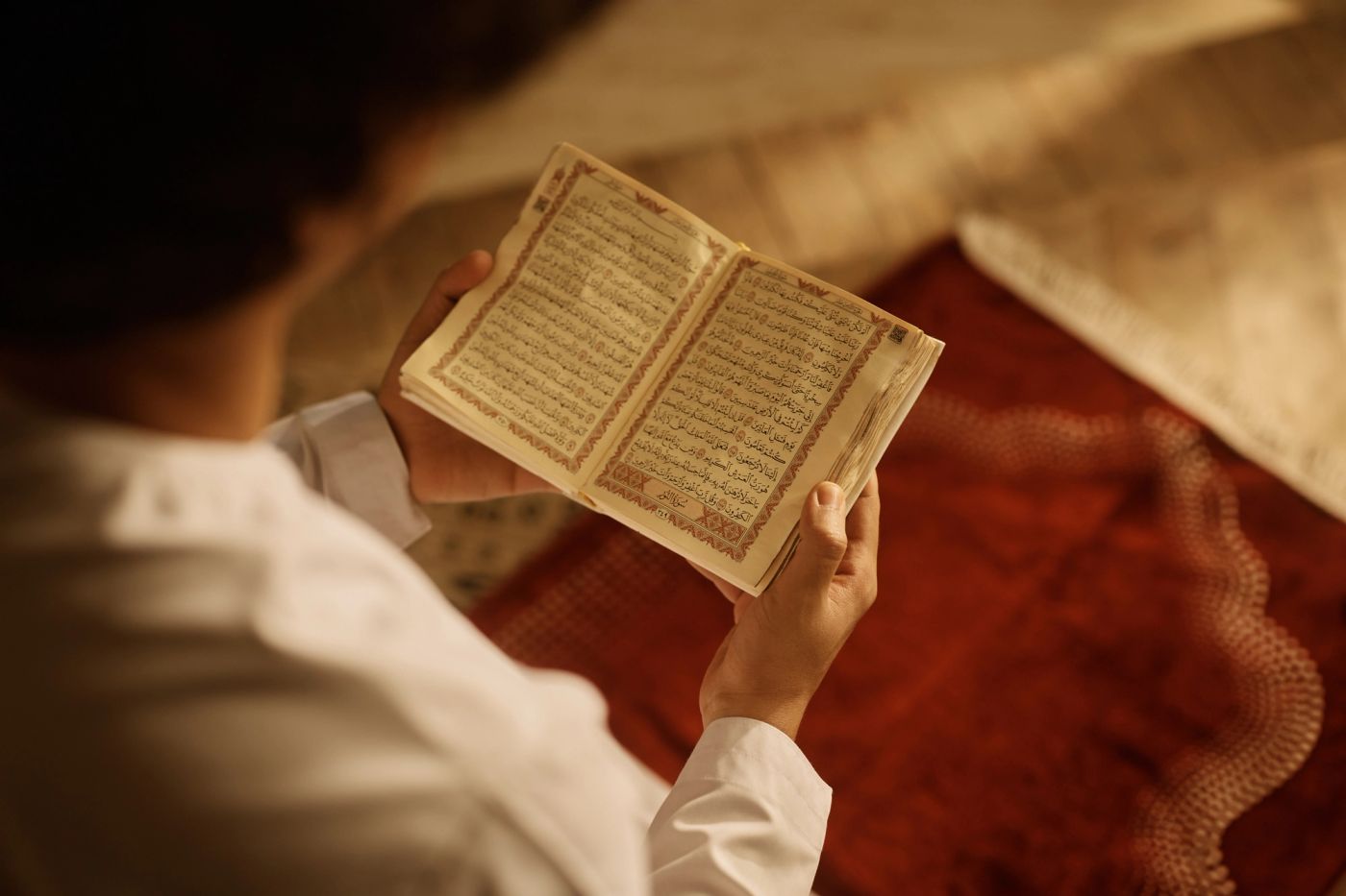 Een man leest in een opengeslagen Qoer'aan, met zijn hand op de bladzijde