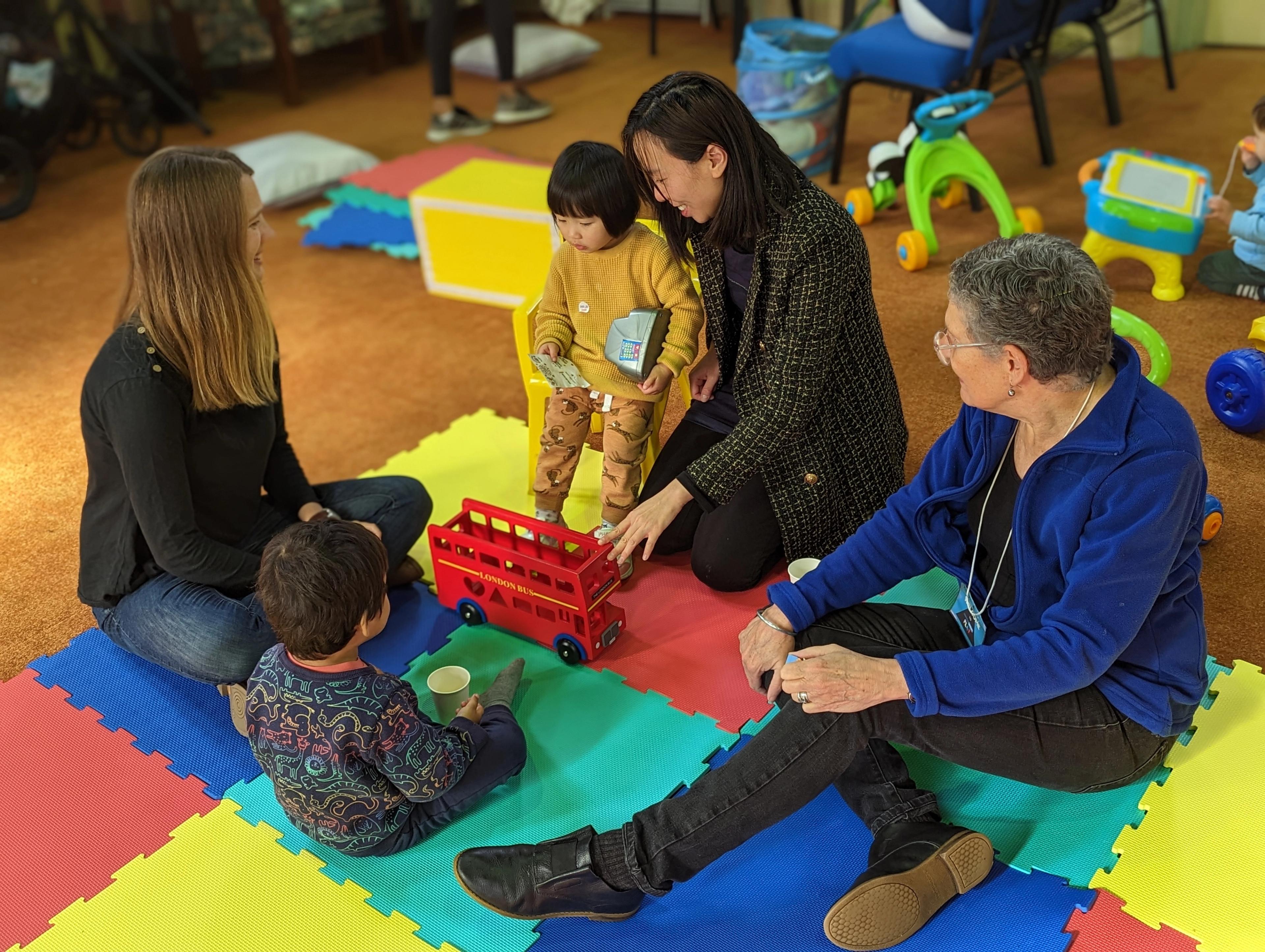 A group of parents and children playing together on a coloured mat