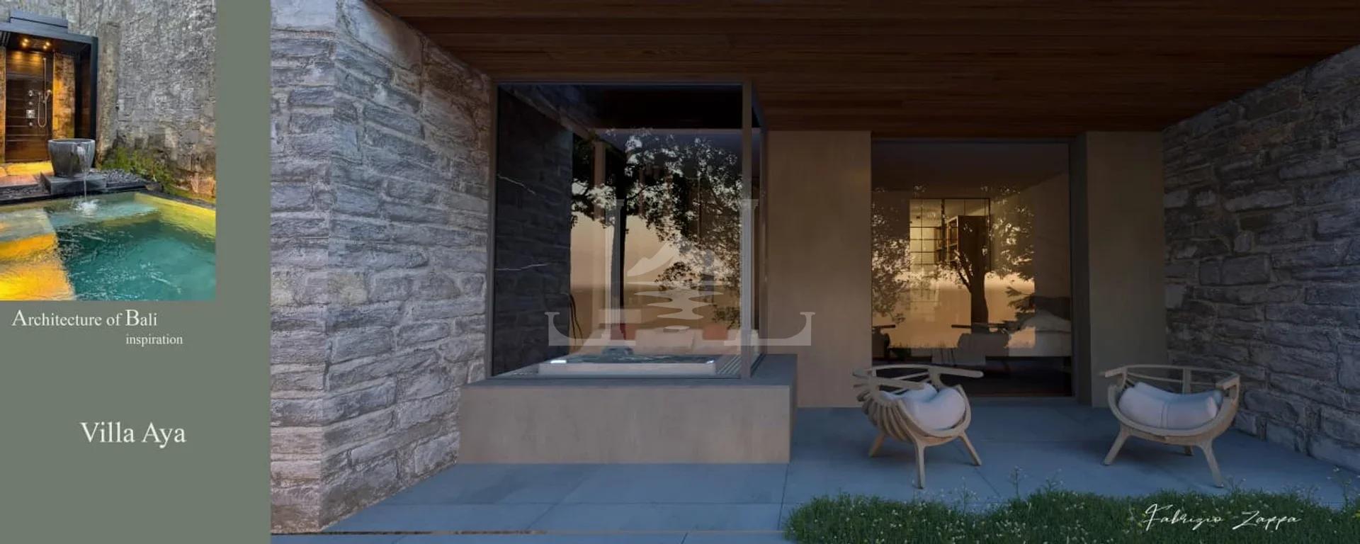 Exterior view of the villa's terrace, showcasing a glass-enclosed hot tub, natural stone walls, and an inviting outdoor seating area.