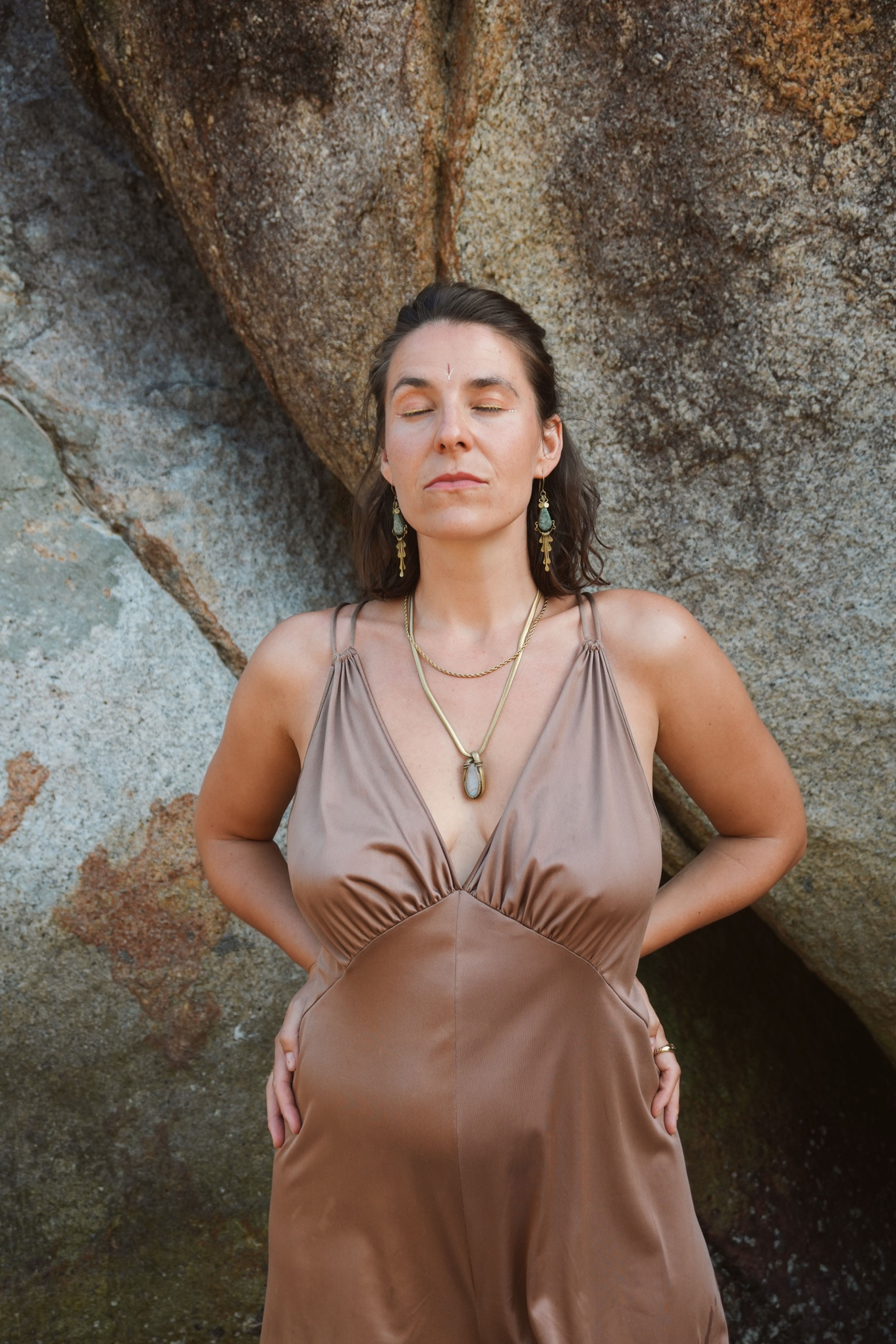 Judith Krüger in a brown dress in front of a large rock