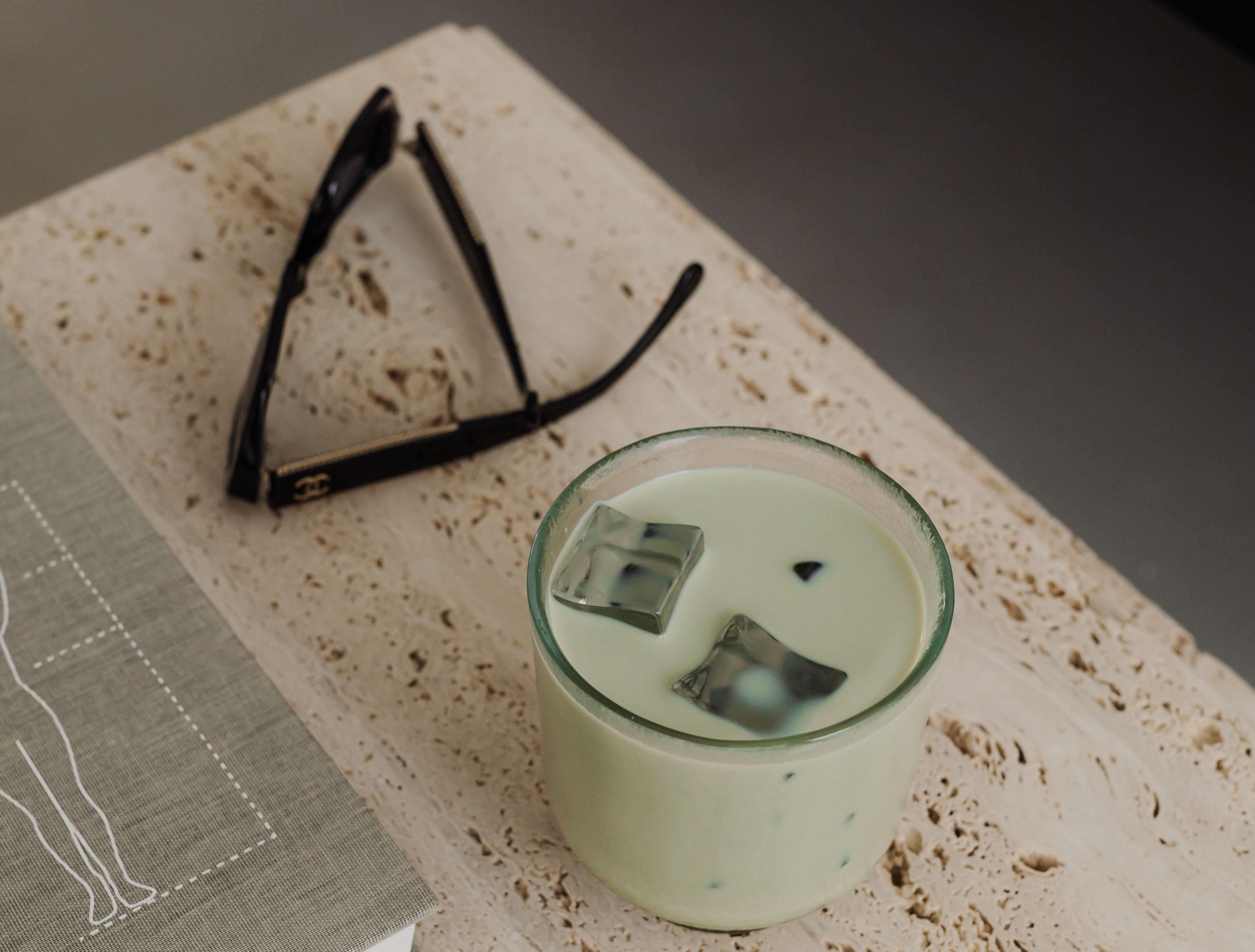 Matcha-Latte und Sonnenbrille auf einem Travertin-Tisch