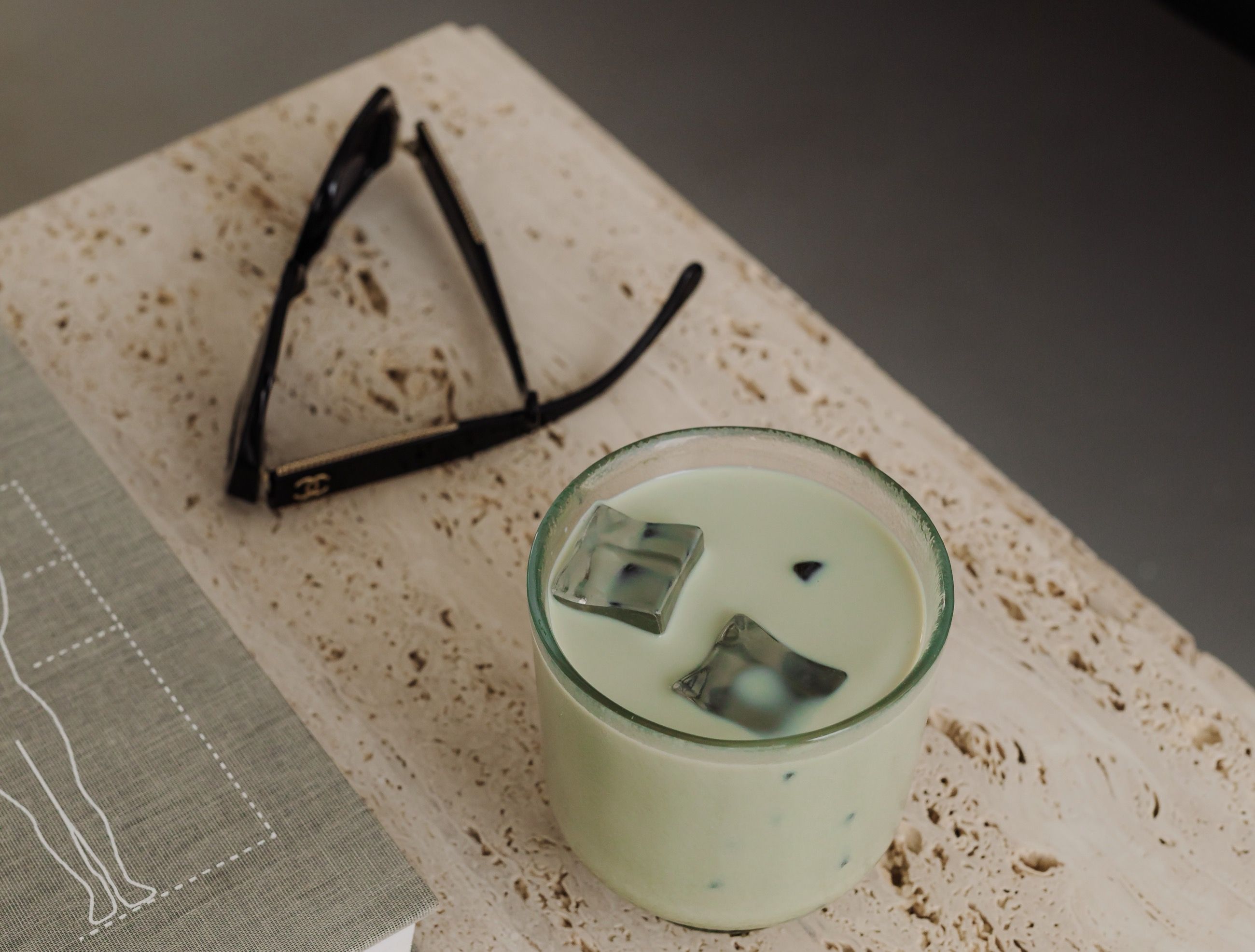 Matcha latte and sunglasses on a travertine table