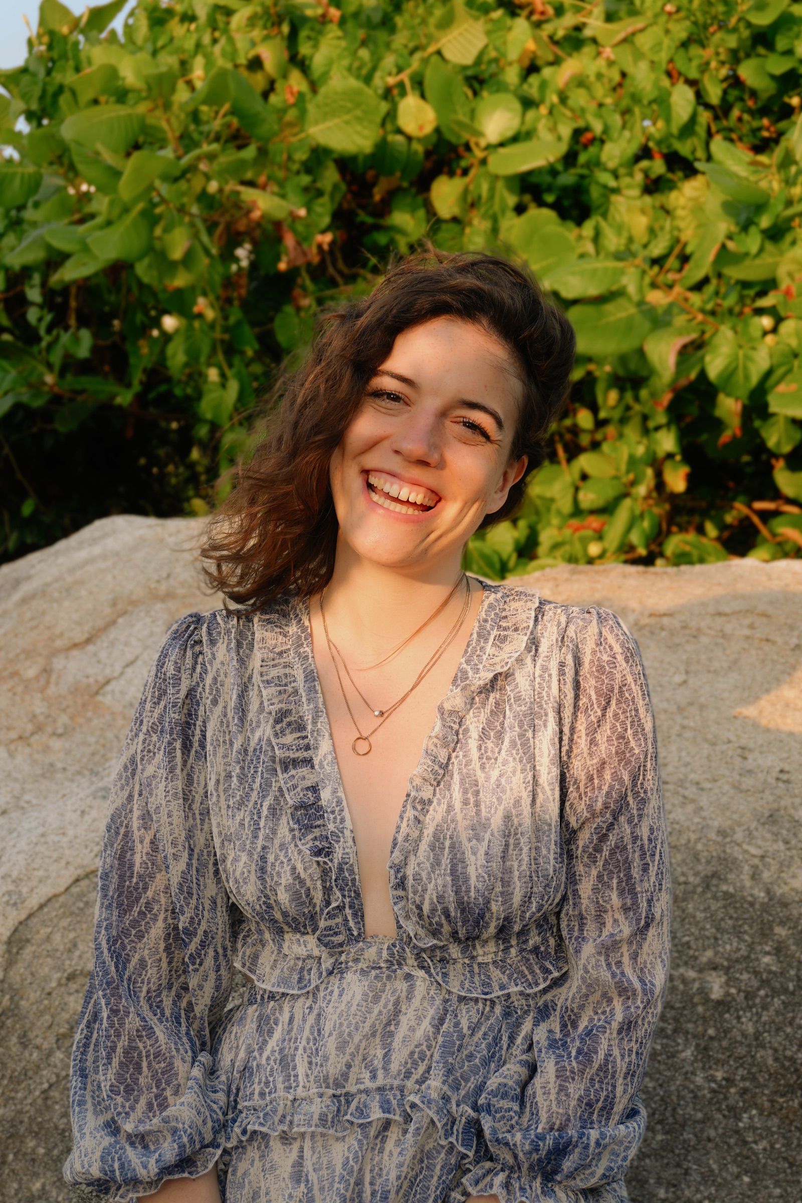 Lena Lambrecht laughing in a blue patterned dress in front of a rock