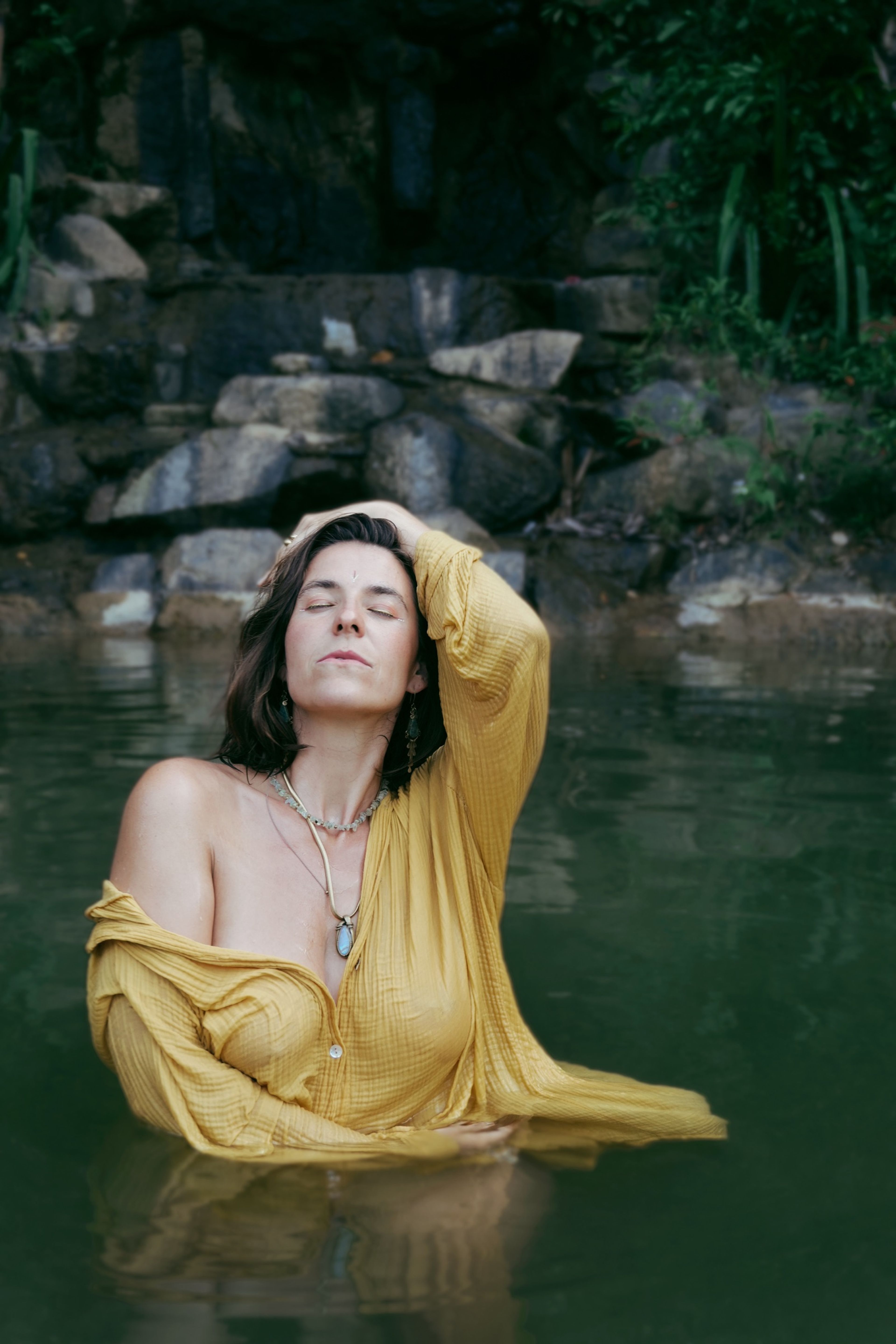 Judith Krüger in a yellow shirt in a jungle waterfall pool