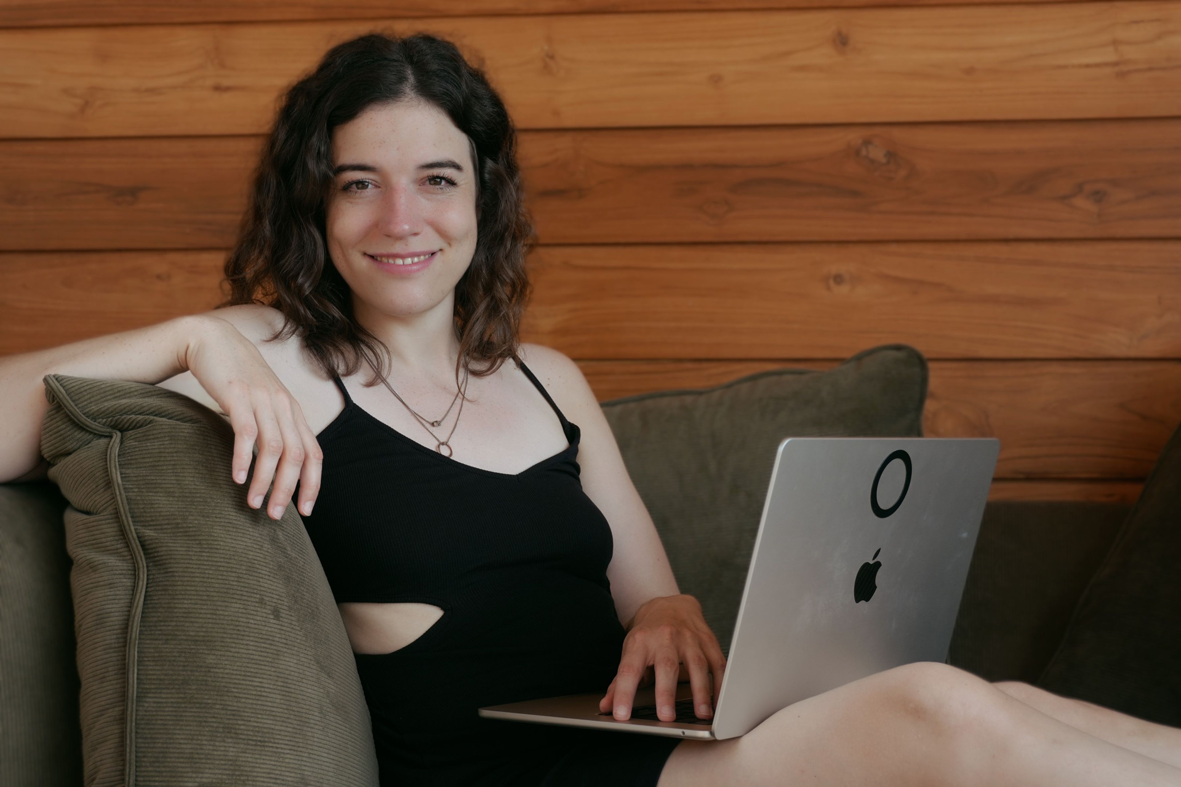 Lena Lambrecht smiling while working on a laptop on a sofa