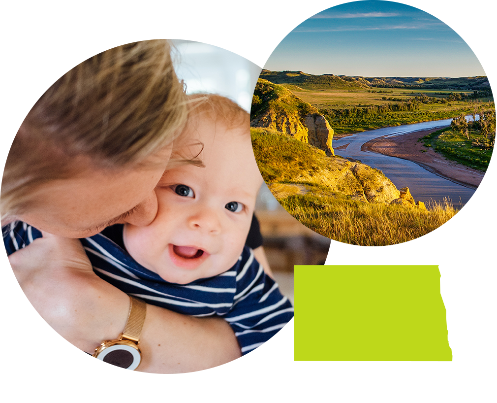 Mother kissing smiling baby next to photo of sunny plains and a ariver in North Dakota.