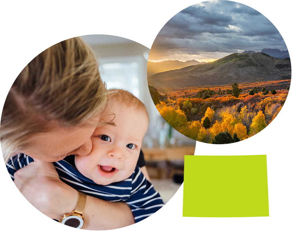 Mother kissing baby next to sunny mountains and yellow plains in Colorado.