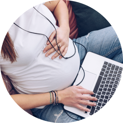 Pregnant woman using a laptop, with one hand over her stomach.