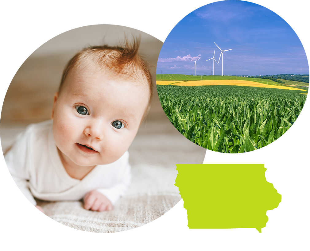 Smiling baby boy with red hair next to wind turbines in a field in Iowa.