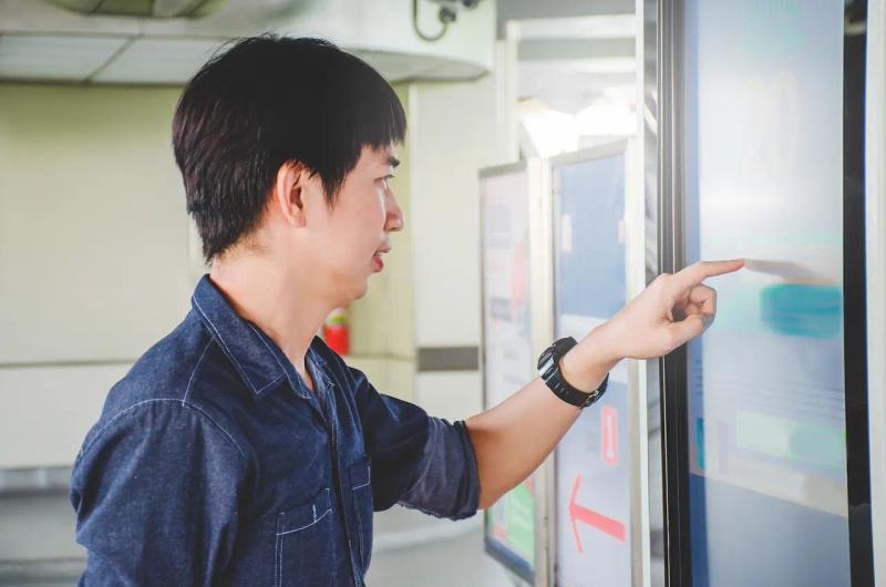 Man near an interactive kiosk touch the screen