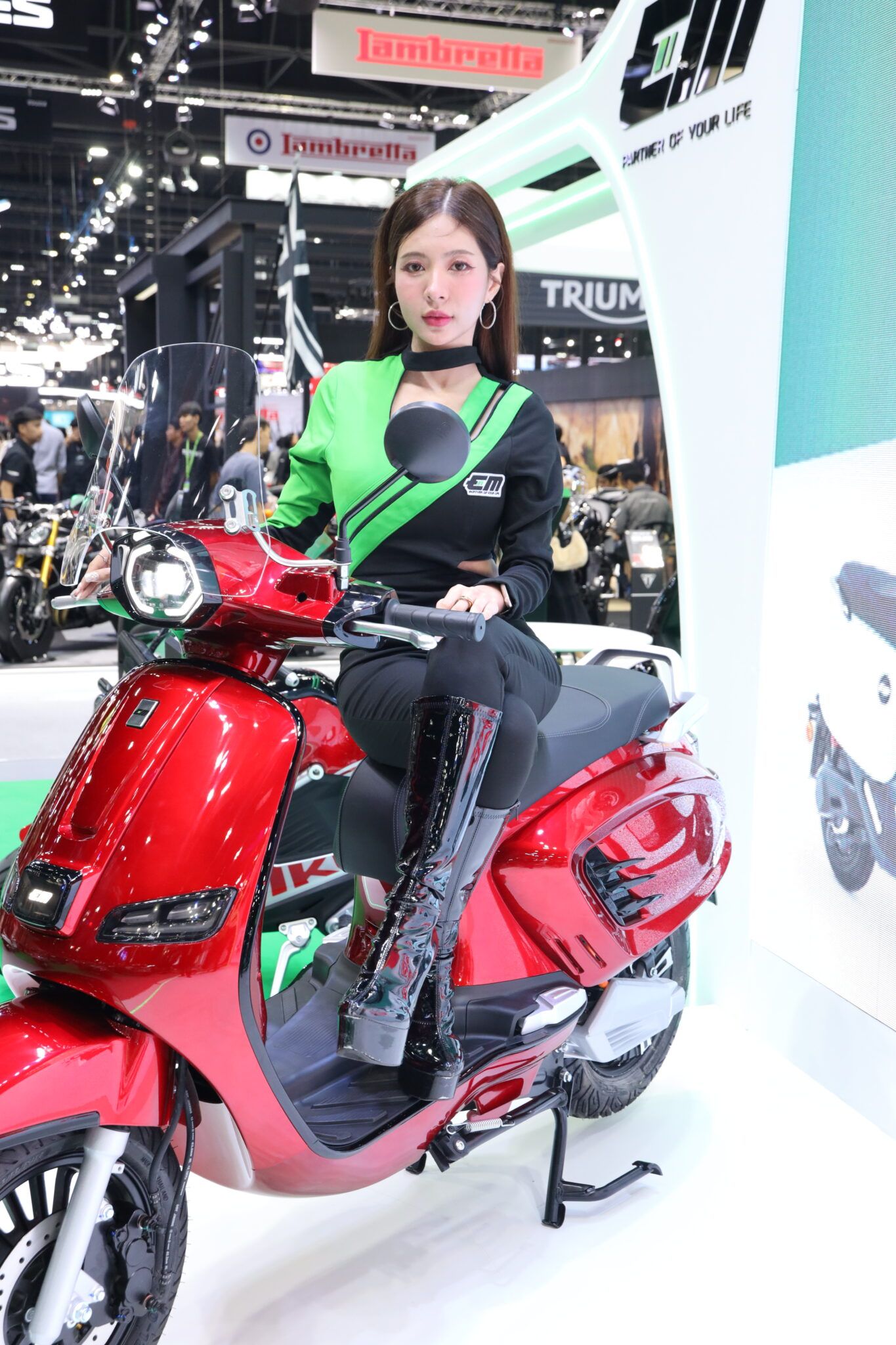 ภาพพนักงานต้อนรับนั่งโพสท่าบนมอเตอร์ไซค์ไฟฟ้า EM ENZO