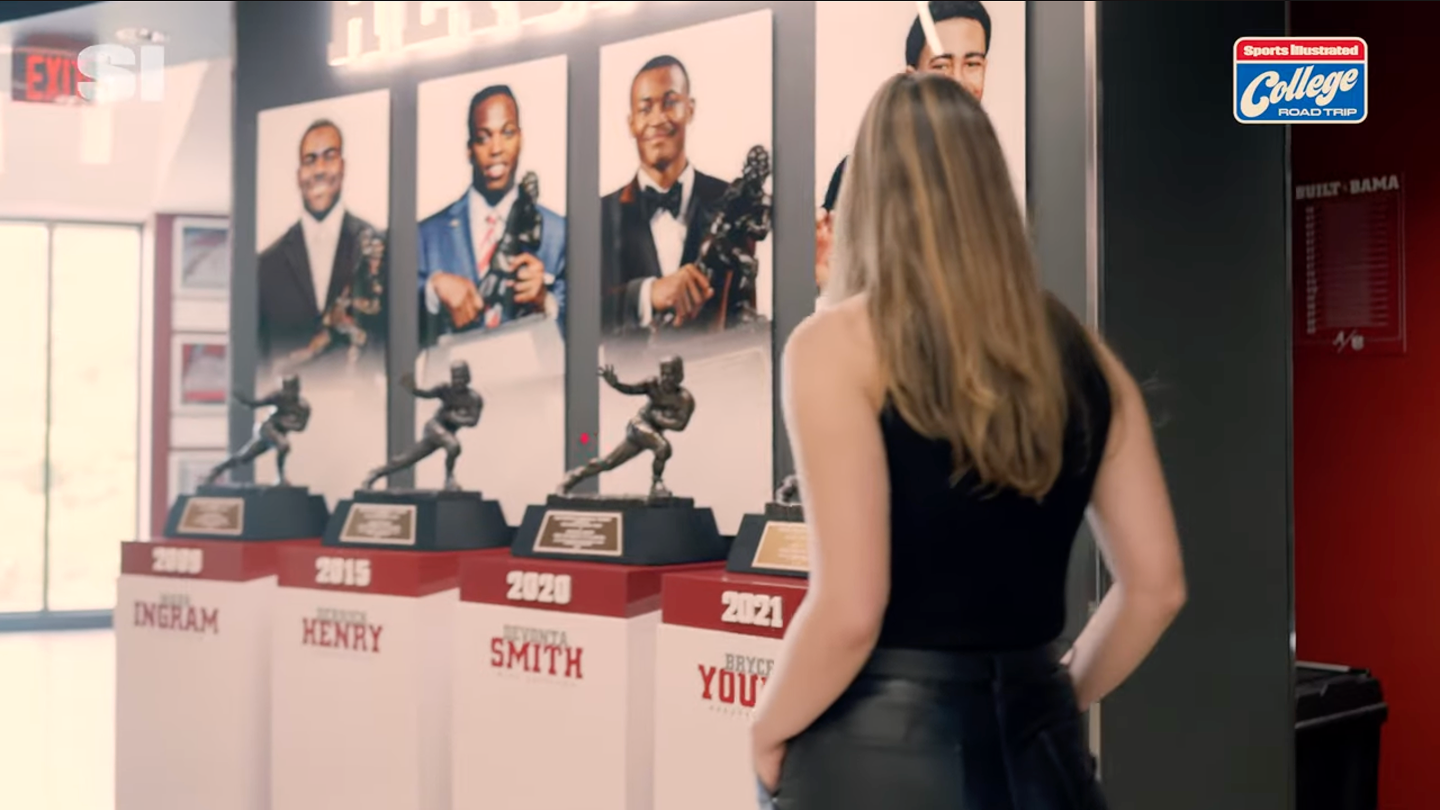 lady admiring past Heisman Trophy winners
