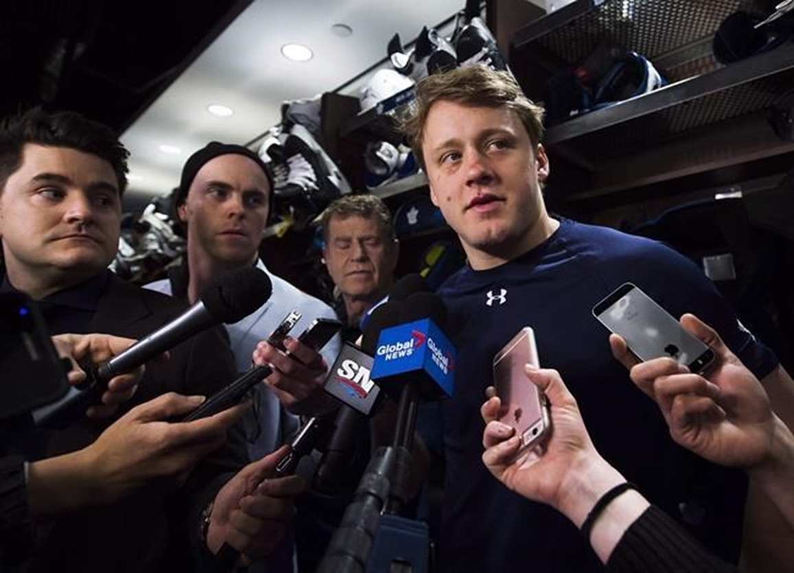 player surrounded by reporters in locker room