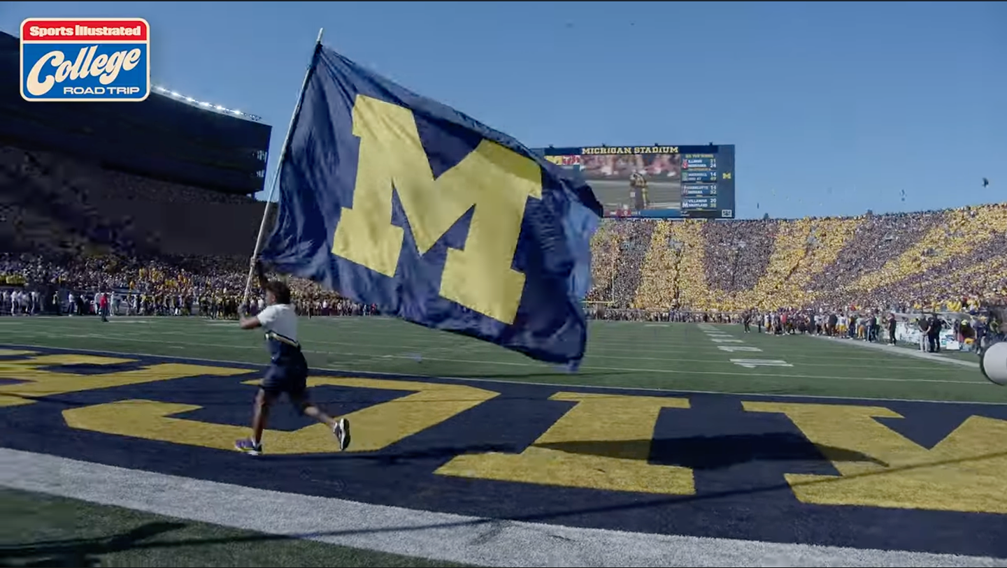 cheerleader with flag running in Michigan football stadium