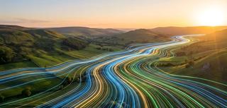 Digital Light Trails Flowing Across Lush Green Landscape at Sunset, Symbolizing Data Connectivity and Technology's Integration with Nature 