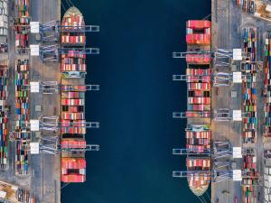 Aerial drone shot of crane loading containers onto cargo ship at Laem Chabang Port.