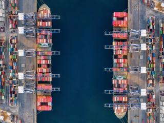 Aerial drone shot of crane loading containers onto cargo ship at Laem Chabang Port.