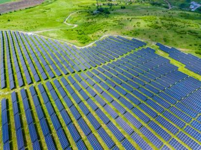 Hillside solar installations integrate seamlessly with lush fields. Aerial view showcasing renewable energy infrastructure harmoniously embedded in pastoral
