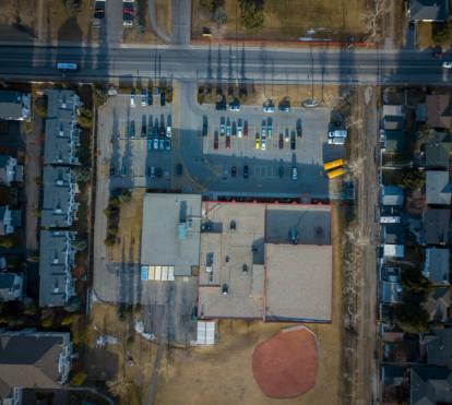 Aerial photo of residential houses a larger community building beside a busier road