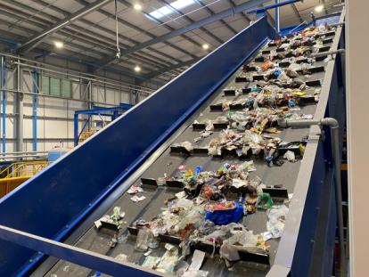 A recycling facility conveyor belt with waste