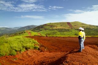 Mine workers standing on mountain top surrounded by soil and rolling hills
