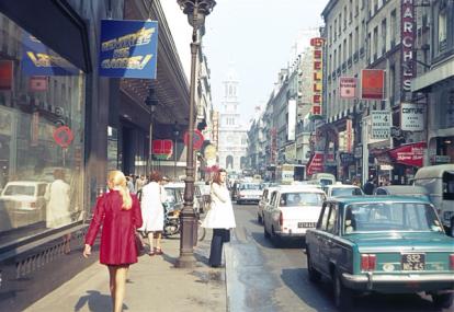 Paris, France street with pedestrians, traffic, shops and buildings in 1978.