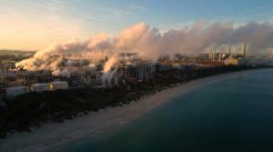 A coastal city with a lot of smoke coming out of it