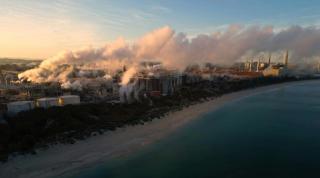 A coastal city with a lot of smoke coming out of it