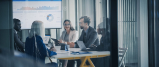 Business Team Meets in a Glass Conference Room to Review Dashboards