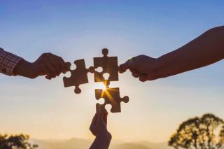 three hands holding puzzle pieces coming together in an alliance
