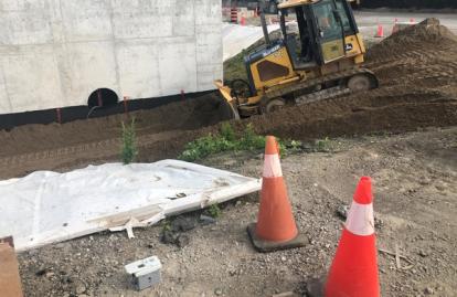 Dirt construction site with bulldozer and road cones