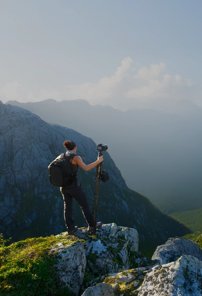 Woman facing hillside, holding camera