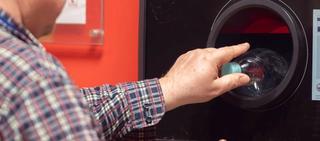 A man depositing a plastic bottle in a deposit return scheme bank